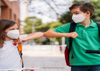 Elbow salute to prevent spread of coronavirus COVID-19. Boy and girl with mask greeting each other on the street during the coronavirus pandemic